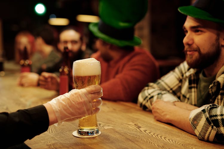 A Barman Serving Beer To A Customer On St. Patrick's Day