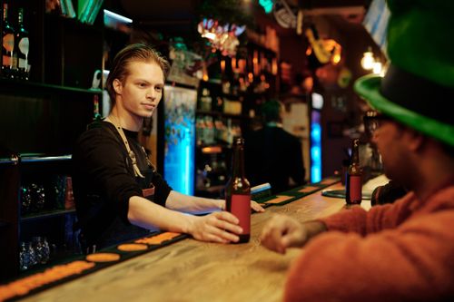 Free A bartender in a pub serving drinks to a customer, creating a lively atmosphere. Stock Photo