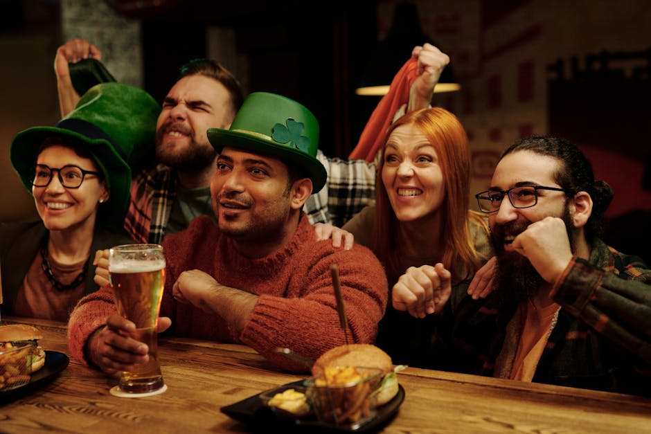 A group of friends in leprechaun hats cheerfully celebrate St. Patrick's Day at a pub.