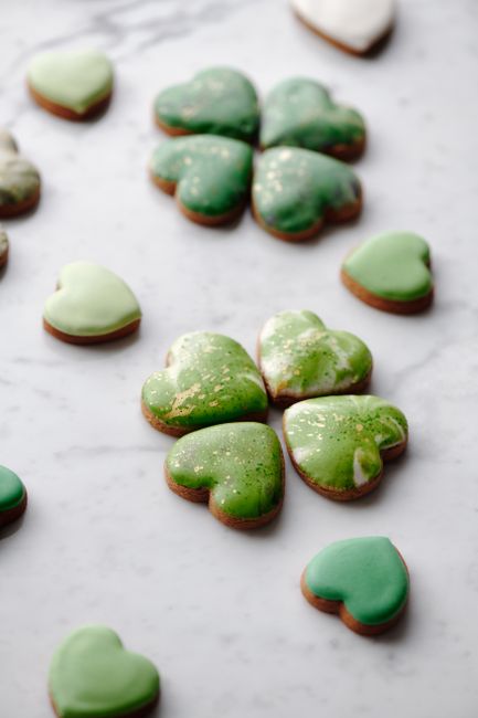 Festive green cookies in heart and clover shapes on marble; perfect for St. Patrick's Day.