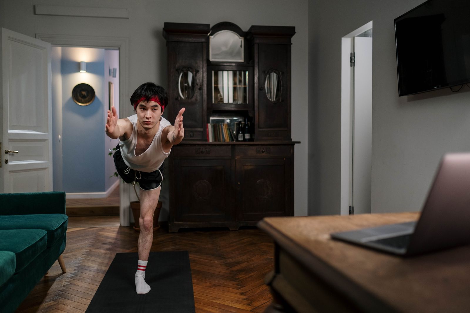 Man practicing a yoga pose during a live online workout session in his living room