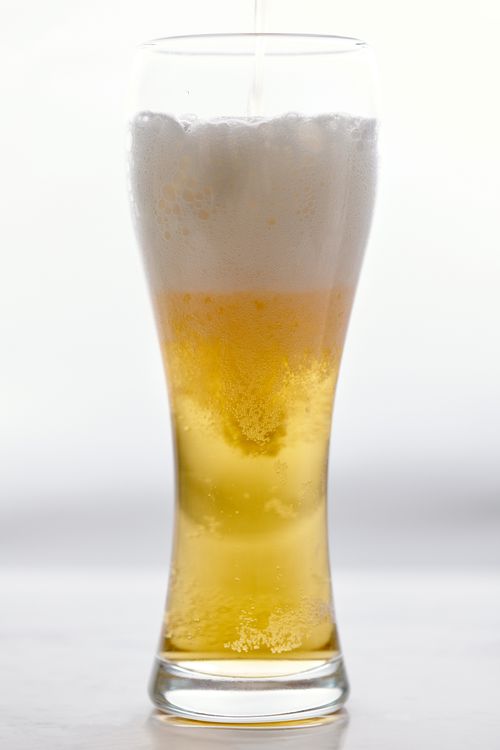 Free A close-up of a tall glass filled with beer and a foamy head, isolated on a white background. Stock Photo