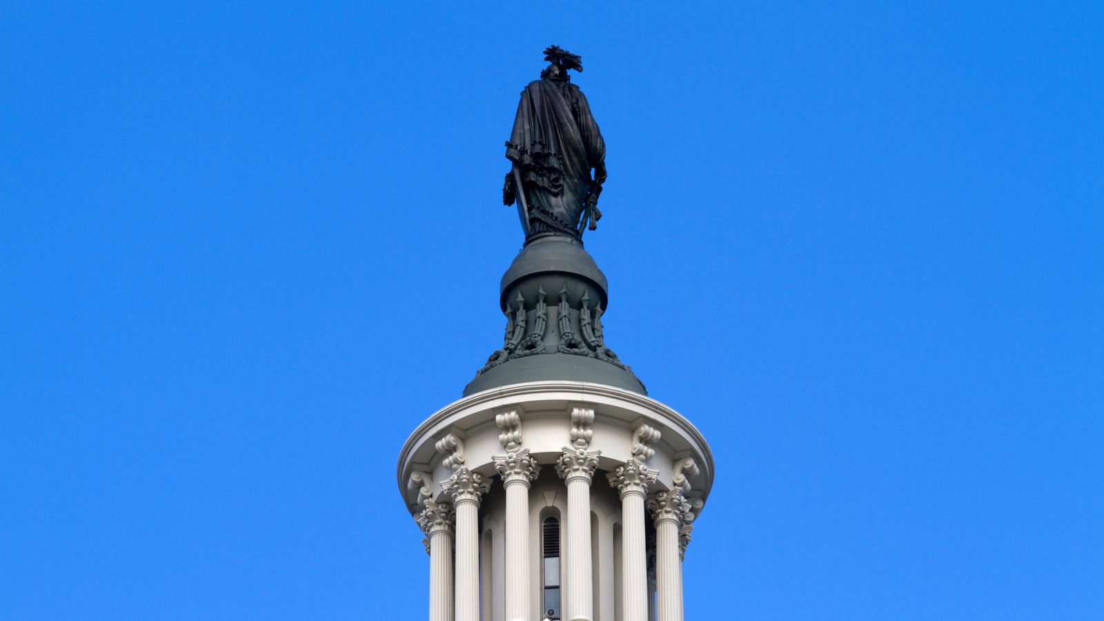 Close-up of the Statue of Freedom on the U.S. Capitol Dome against a clear blue sky.