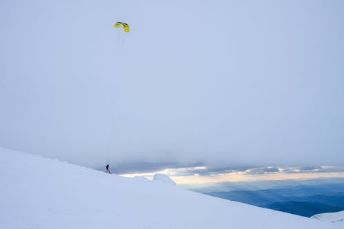 A Person Doing Ski-base Jumping from the Snow Covered Mountain