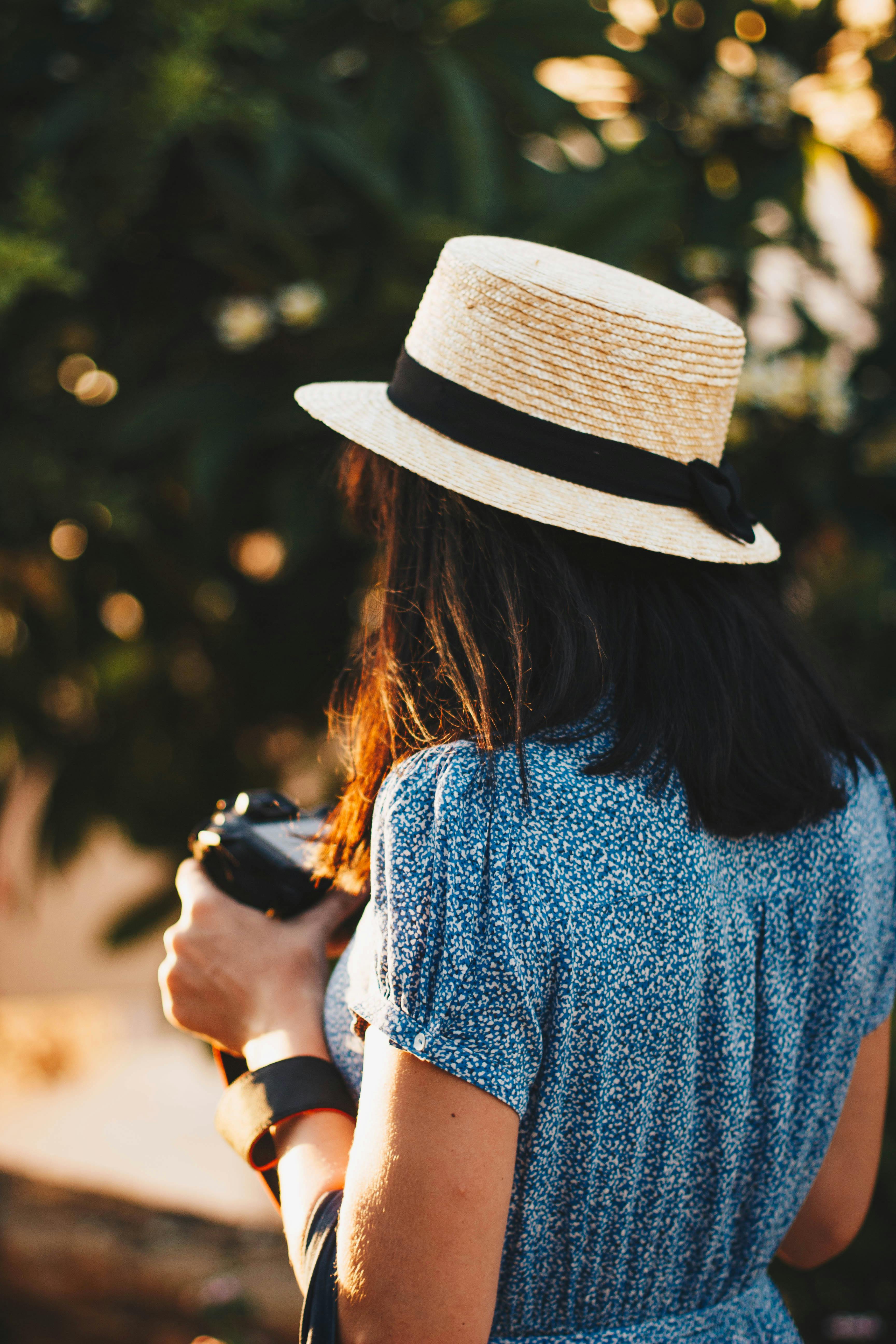 一位女士戴着草帽，在户外将相机聚焦，拥抱夏日的休闲与探索