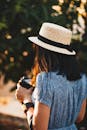 一位女士戴着草帽，在户外将相机聚焦，拥抱夏日的休闲与探索