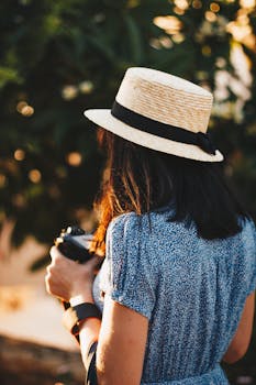 一位女士戴着草帽，在户外将相机聚焦，拥抱夏日的休闲与探索