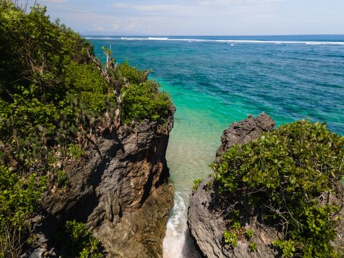 Free Stunning view of a lush green cliff meeting the vibrant turquoise ocean under a clear blue sky. Stock Photo