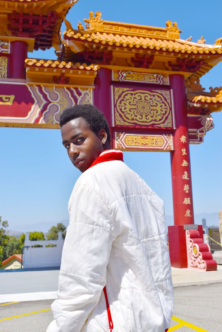 Black Man Against Asian Arch With Ornament In Sunny Town