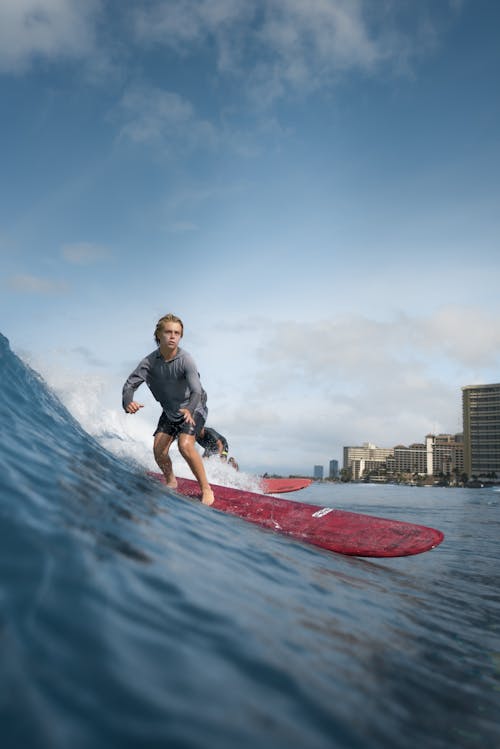 Sporty teenage boy surfing on sea waves