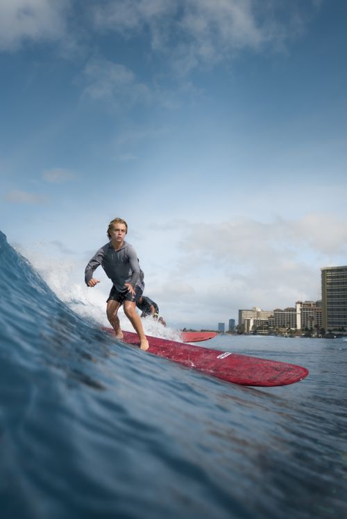 Free Energetic teenage boy in wet clothes on surfboarding surfing sea waves on sunny day in modern coastal city Stock Photo