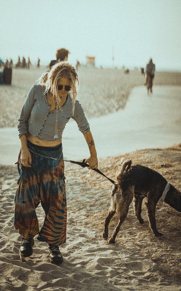 Informal Woman Walking Dog On Sandy Beach