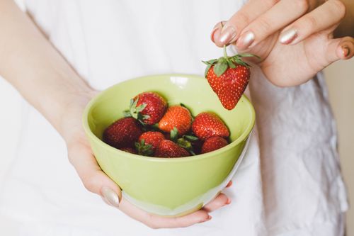 Free A close-up of a hand holding a green bowl filled with ripe strawberries, showcasing healthy lifestyle. Stock Photo