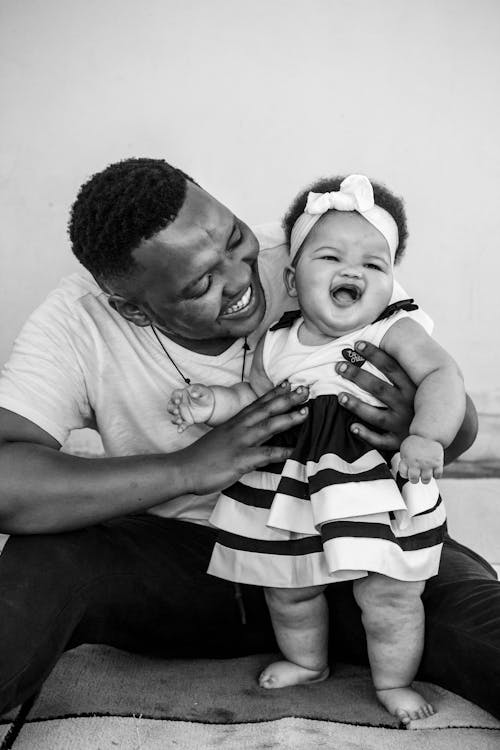 Grayscale Photo of a Father Laughing with His Daughter