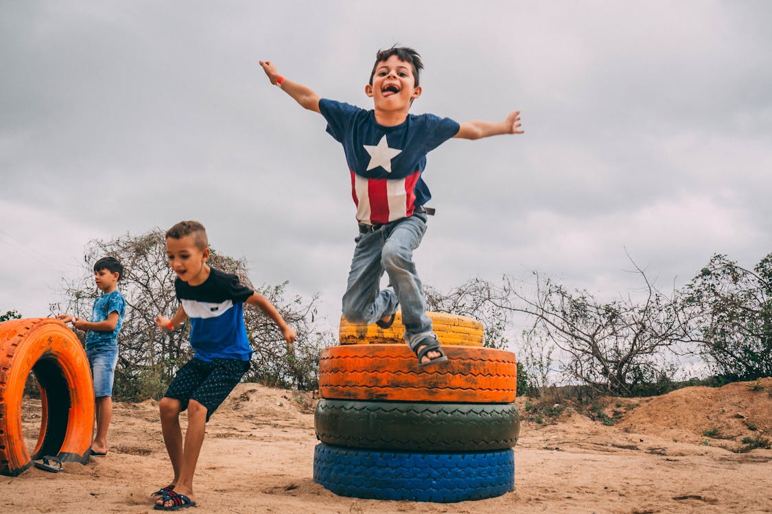 Free Photograph of Kids Playing Near Colorful Tires Stock Photo