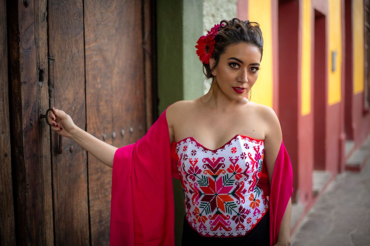 woman in vibrant traditional dress posing against rustic wooden door