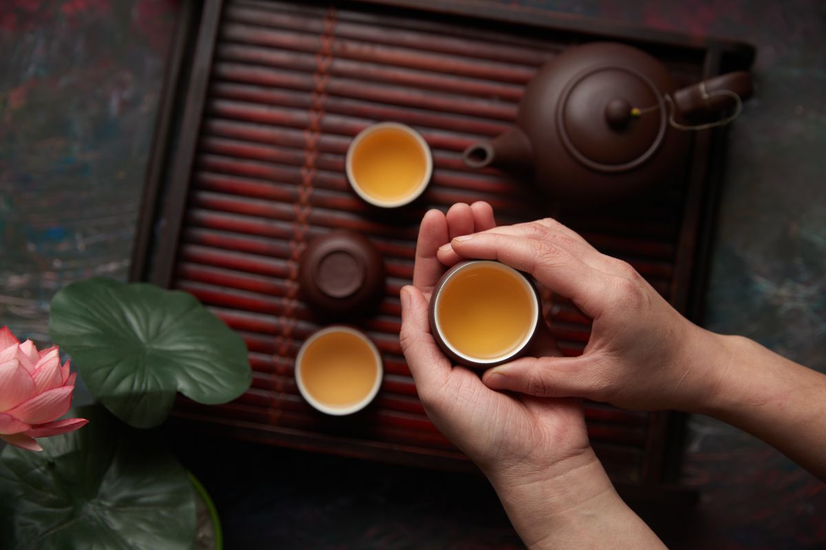A person holding a warm ceramic cup during a tea ceremony