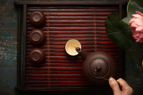 Person Pouring Tea From Brown Tea Pot