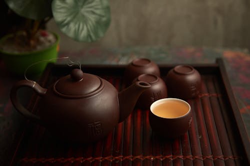 Free Brown Cup Beside Brown Ceramic Teapot on Wooden Table Stock Photo