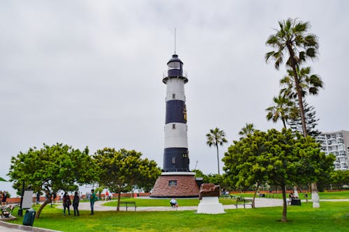 People Walking Near Blue and White Striped Lighthouse