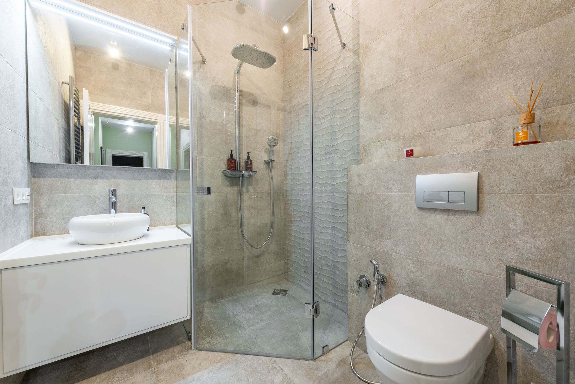 Charlotin Plumbing Services - Contemporary bathroom featuring a glass shower, beige tiles, and stylish fixtures for a modern aesthetic.