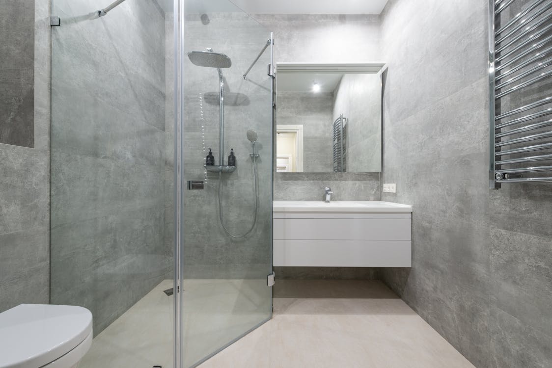 Modern shower room interior with glass walls against washstand