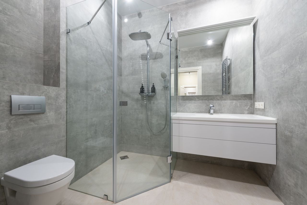 A modern grey bathroom with a wall-hung toilet, concealed cistern and dual-flush plate