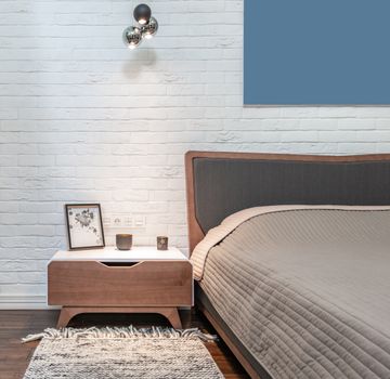 Modern bedroom interior with furniture against whitewashed brick wall