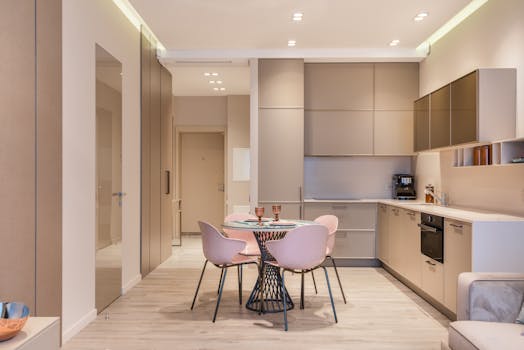 Contemporary minimalist kitchen with round dining table and pastel chairs, ideal for urban apartments.