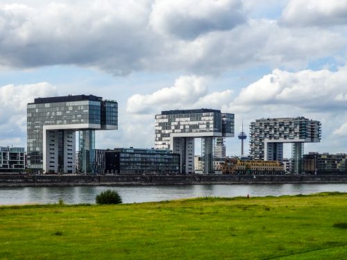 Free Modern Kranhaus buildings in Cologne, Germany, with lush green riverfront. Stock Photo