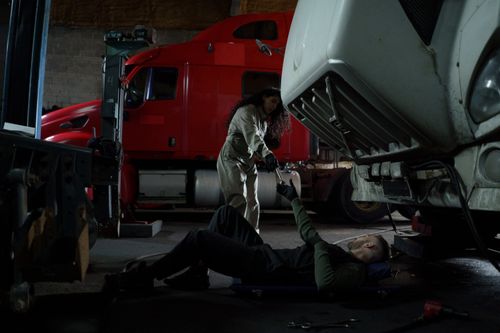 Free Two mechanics working together to repair a truck in a dimly lit garage setting. Stock Photo