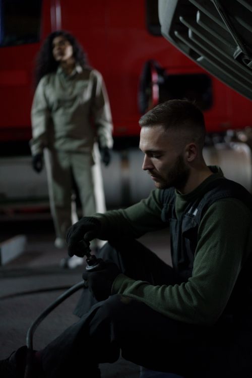 Free Two mechanics working on a vehicle engine inside a garage at night. Stock Photo