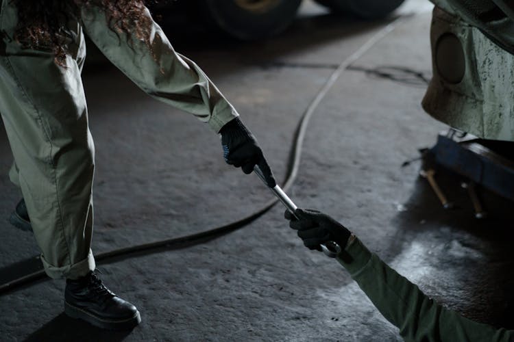 Person Passing Wrench To Repairman On Floor