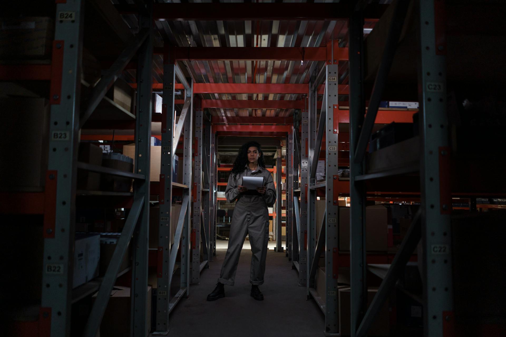 Woman in Gray Uniform Standing inside the Warehouse