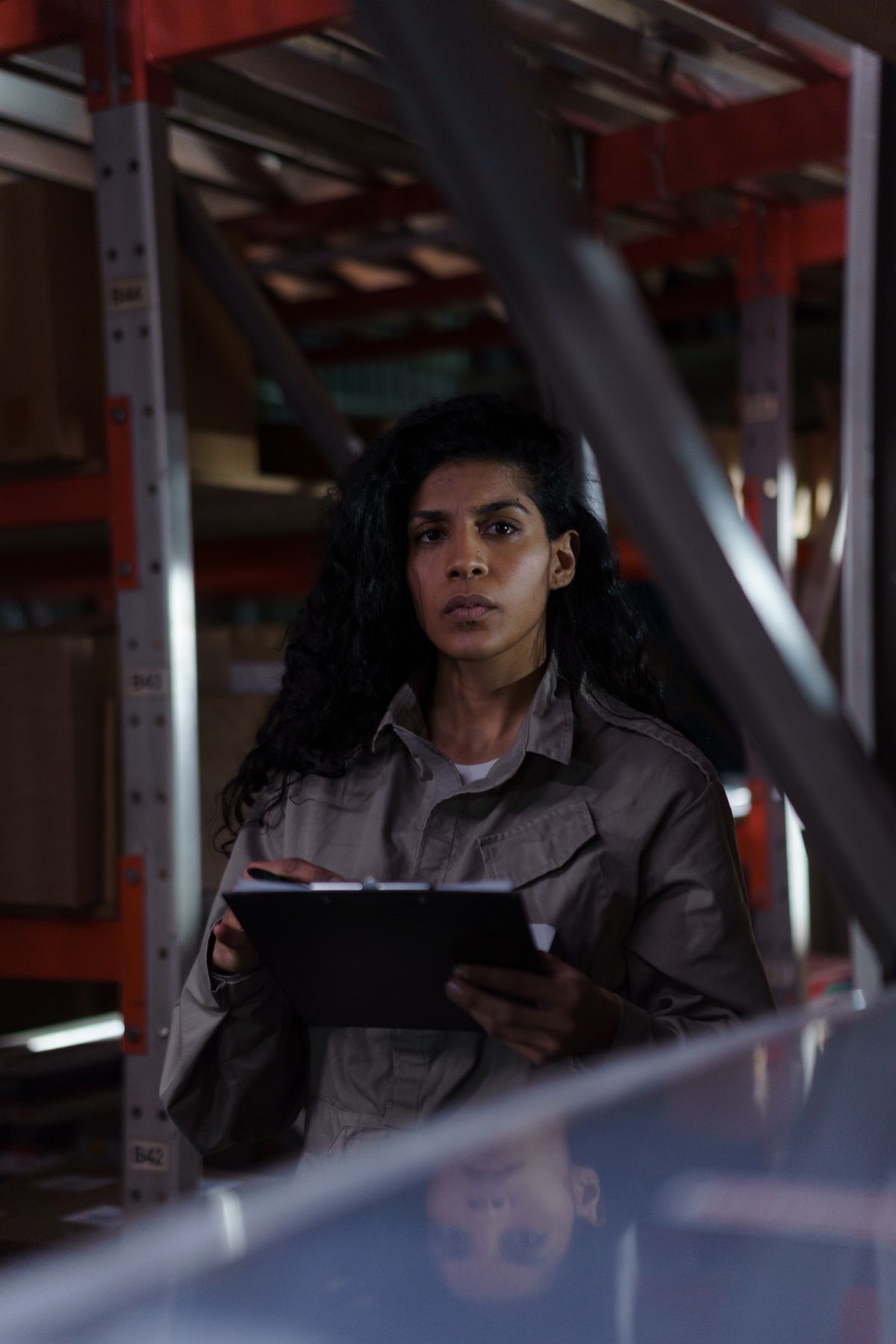 A woman with a clipboard conducting an inventory check in a warehouse aisle