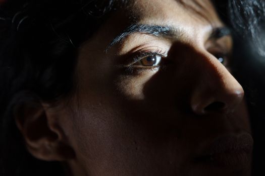 A close-up portrait of a woman with dramatic natural shadows across her face.