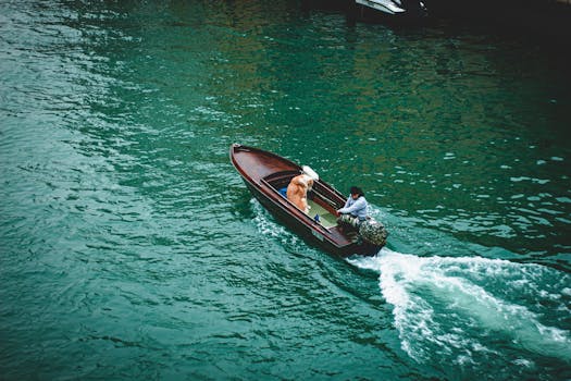 Drone view of a person and dog riding a boat through the vibrant canals of Venice.