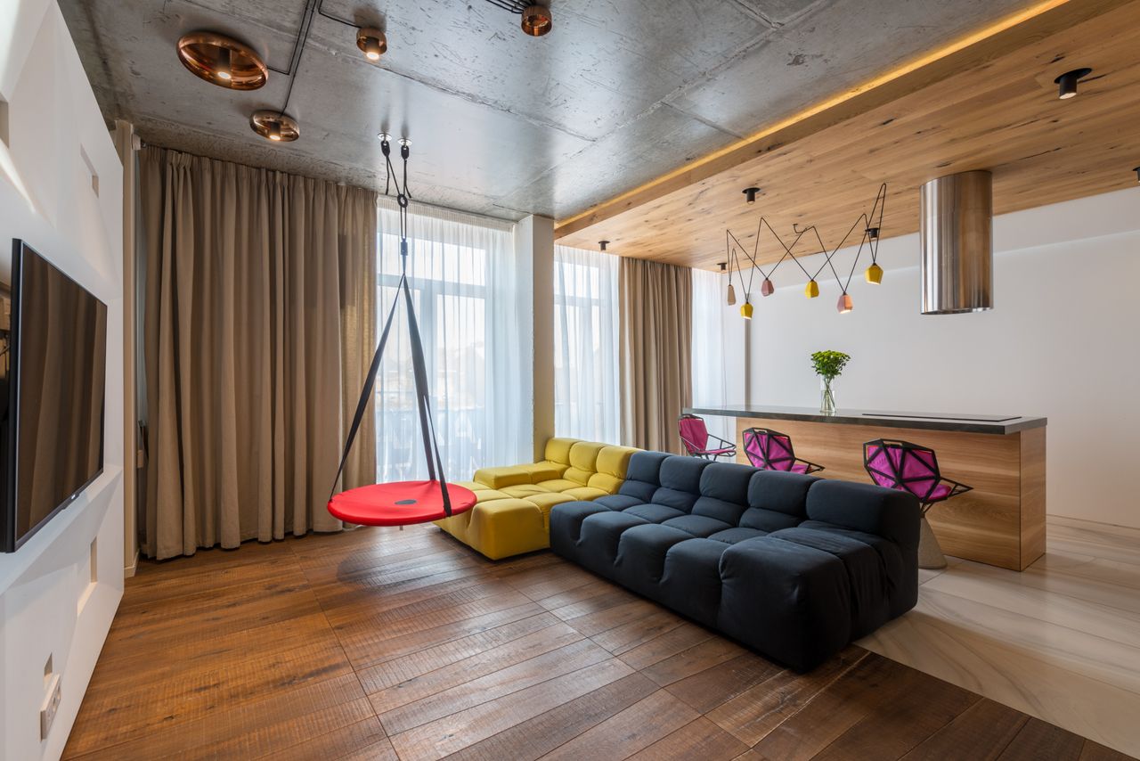 Loft living room with concrete ceiling, copper pendant lights, and colorful sofas