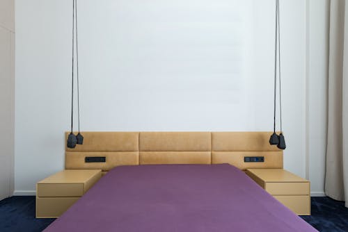 Minimalist interior of contemporary bedroom with bed with headrest and bedsides under stylish lamps