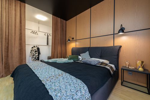 Free Modern interior of bedroom furnished with bed with cushions near bedside and closet with clothes Stock Photo