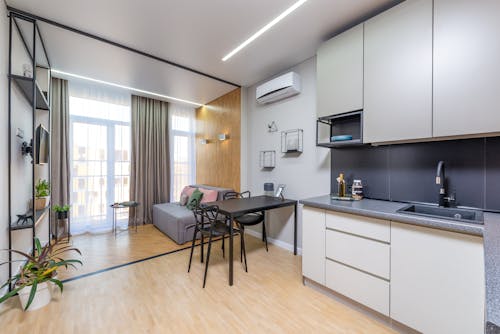 Minimalist interior of spacious flat with kitchen furniture and living zone with panoramic window decorated with curtains