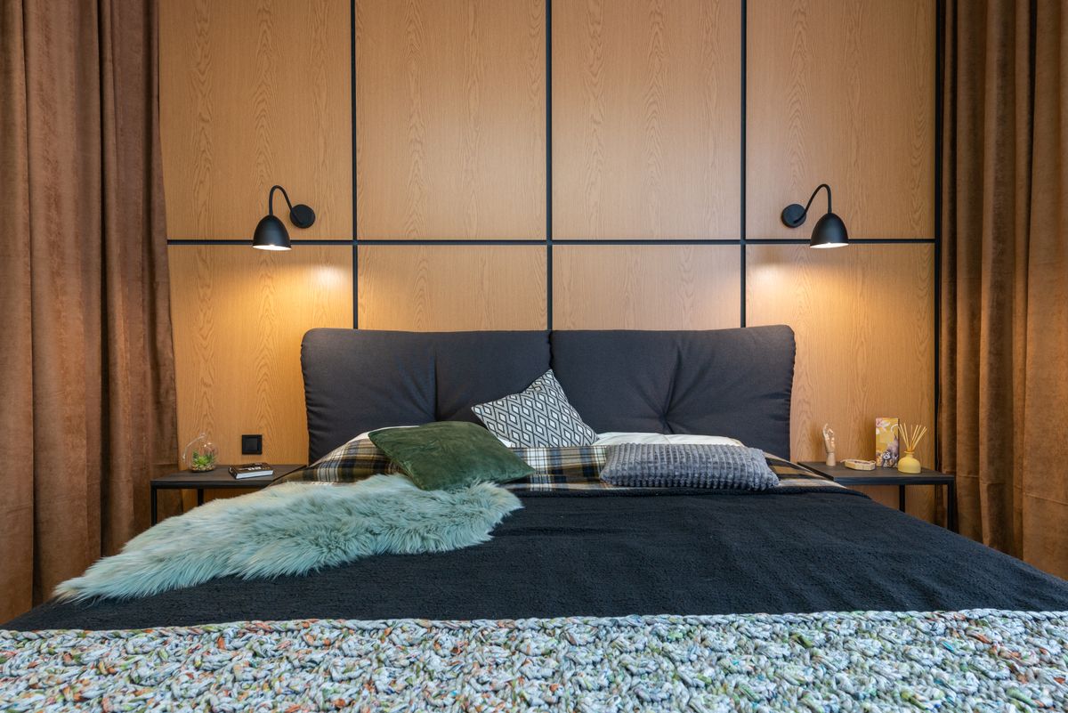 Chambre avec tête de lit en bois et luminaires allumés de chaque côté