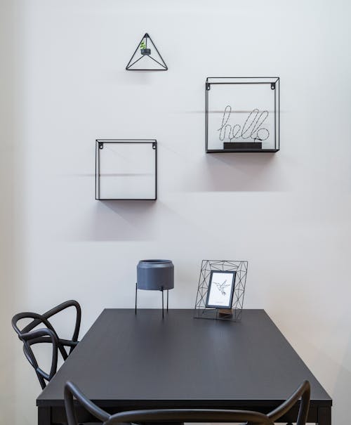 Stylish frames on wall above table and chairs