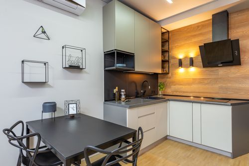 Free Black table with chairs at decorated wall in modern kitchen with appliances and cupboards near glowing lamps in light apartment Stock Photo