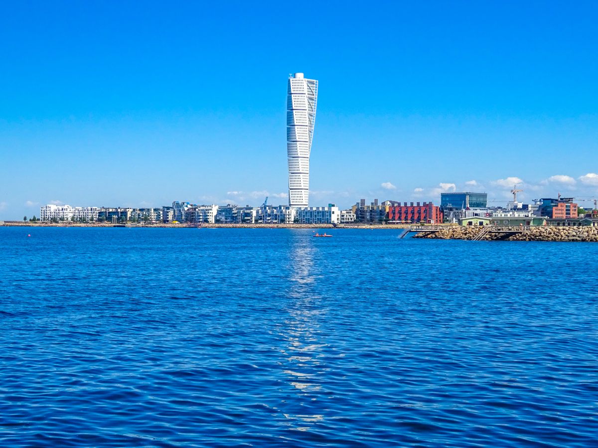 The Turning Torso skyscraper rising above Malmö waterfront, reflected in the Öresund canal — the most recognisable landmark in Skåne