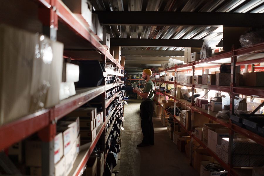 Trabajador organizando repuestos en estantería de bodega