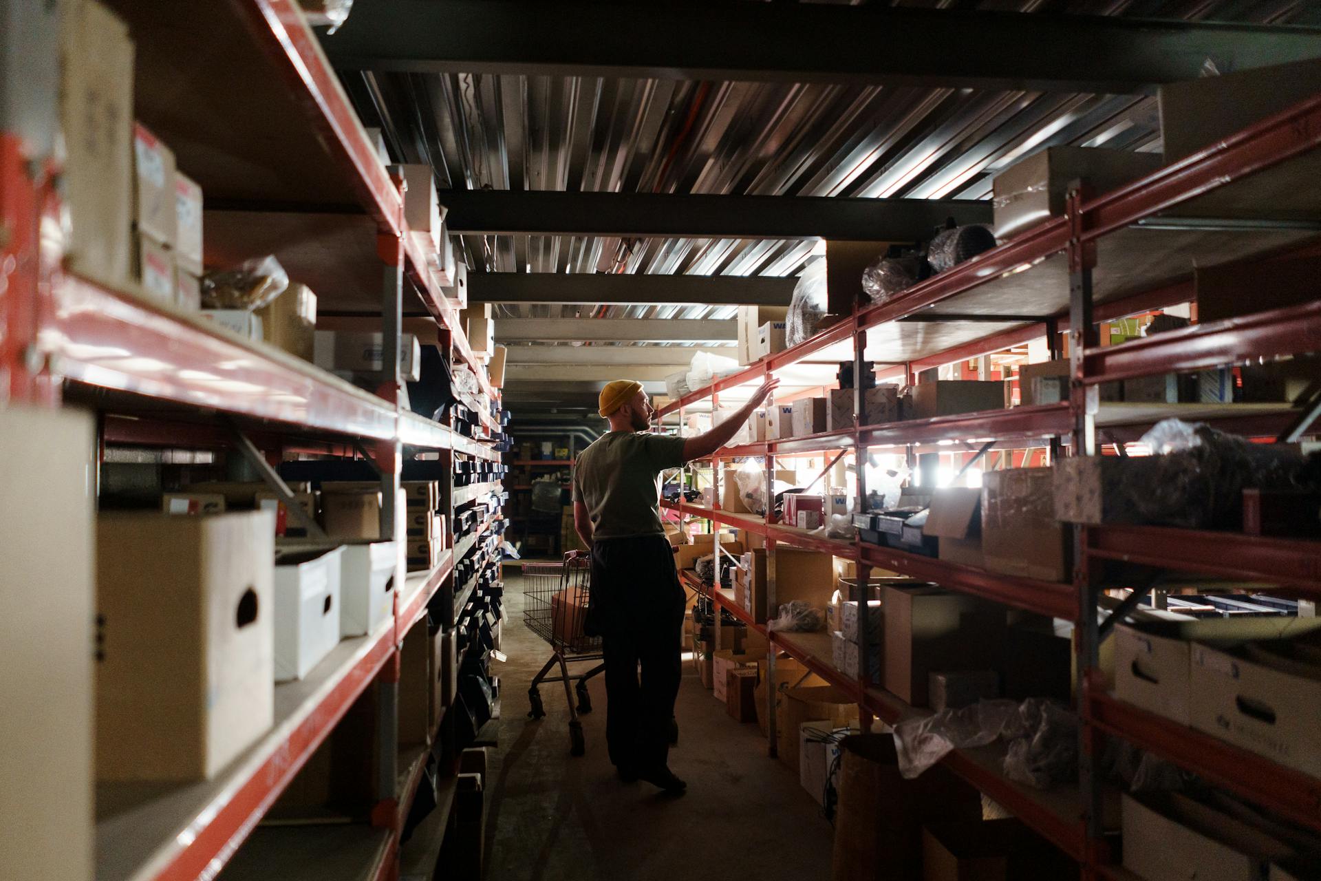 Photo of a Man with a Yellow Beanie Working in a Depot