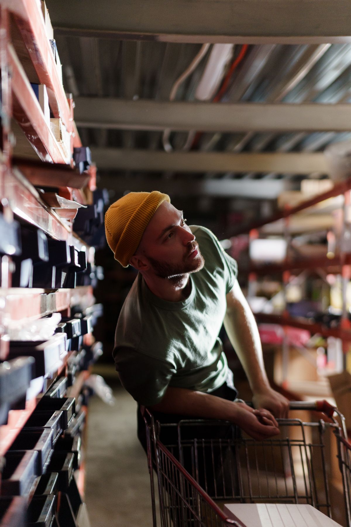 A man with a shopping cart browsing the shelves of a supply warehouse