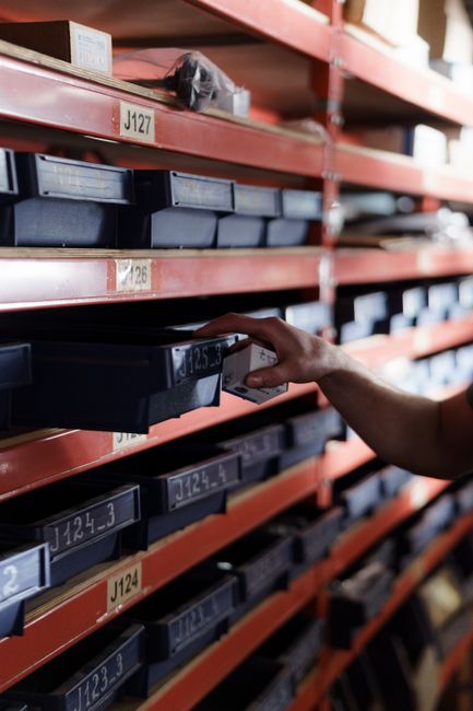 Hand reaching for storage bin in organized warehouse shelving. Perfect for logistics and inventory themes. Hand reaching for storage bin in organized warehouse shelving. Perfect for logistics and inventory themes.