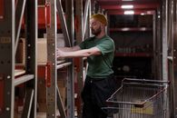 Man in Green Crew Neck T-shirt and Black Pants Standing on a Shopping Cart